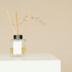 A minimalist reed diffuser with a mockup label on a white pedestal against a neutral background.